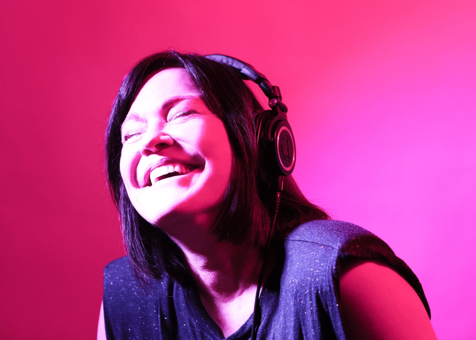 Shell Robinson with headphones, bathed in neon pink light